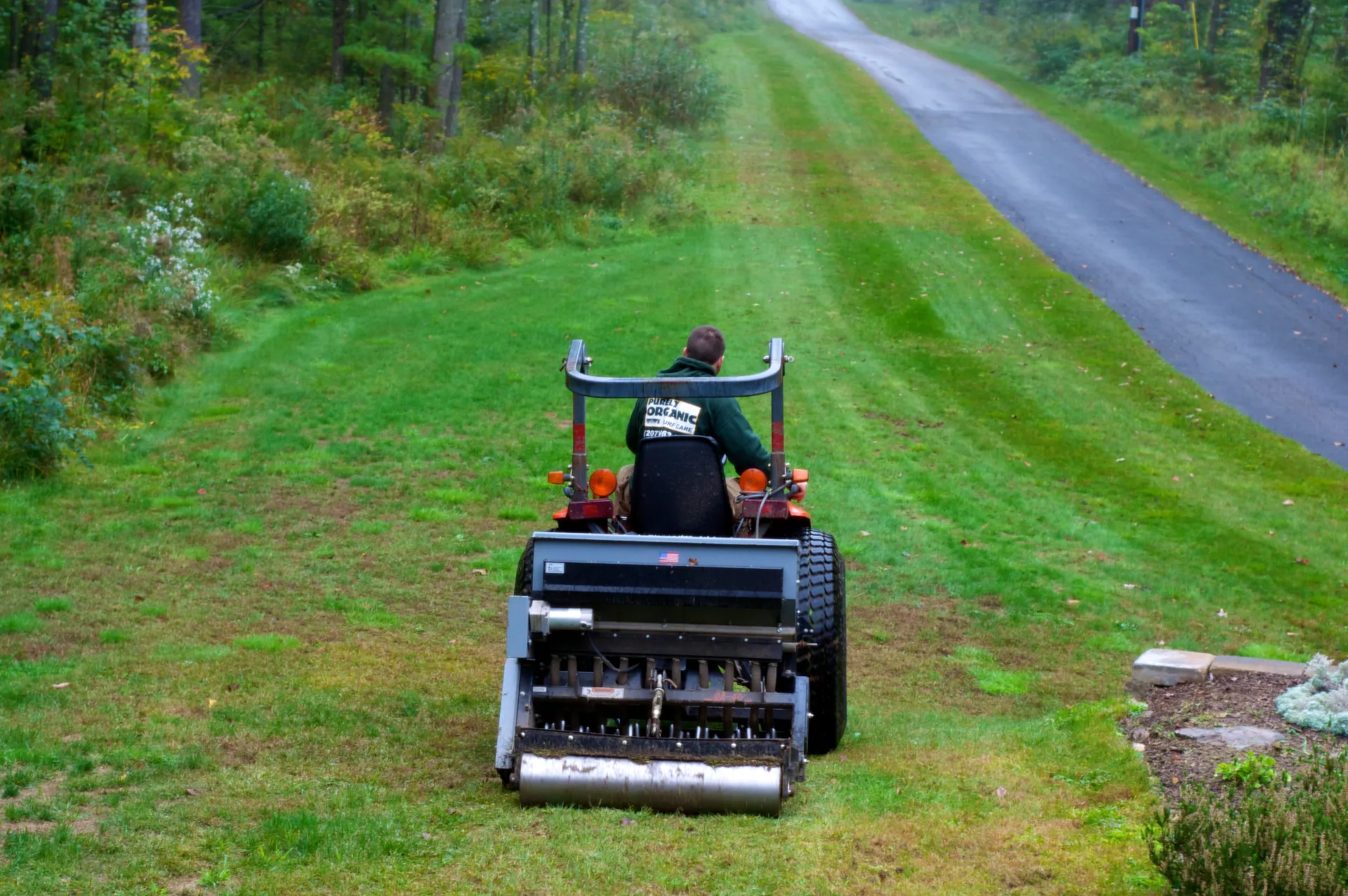 Core aerator machine operating on a residential green lawn