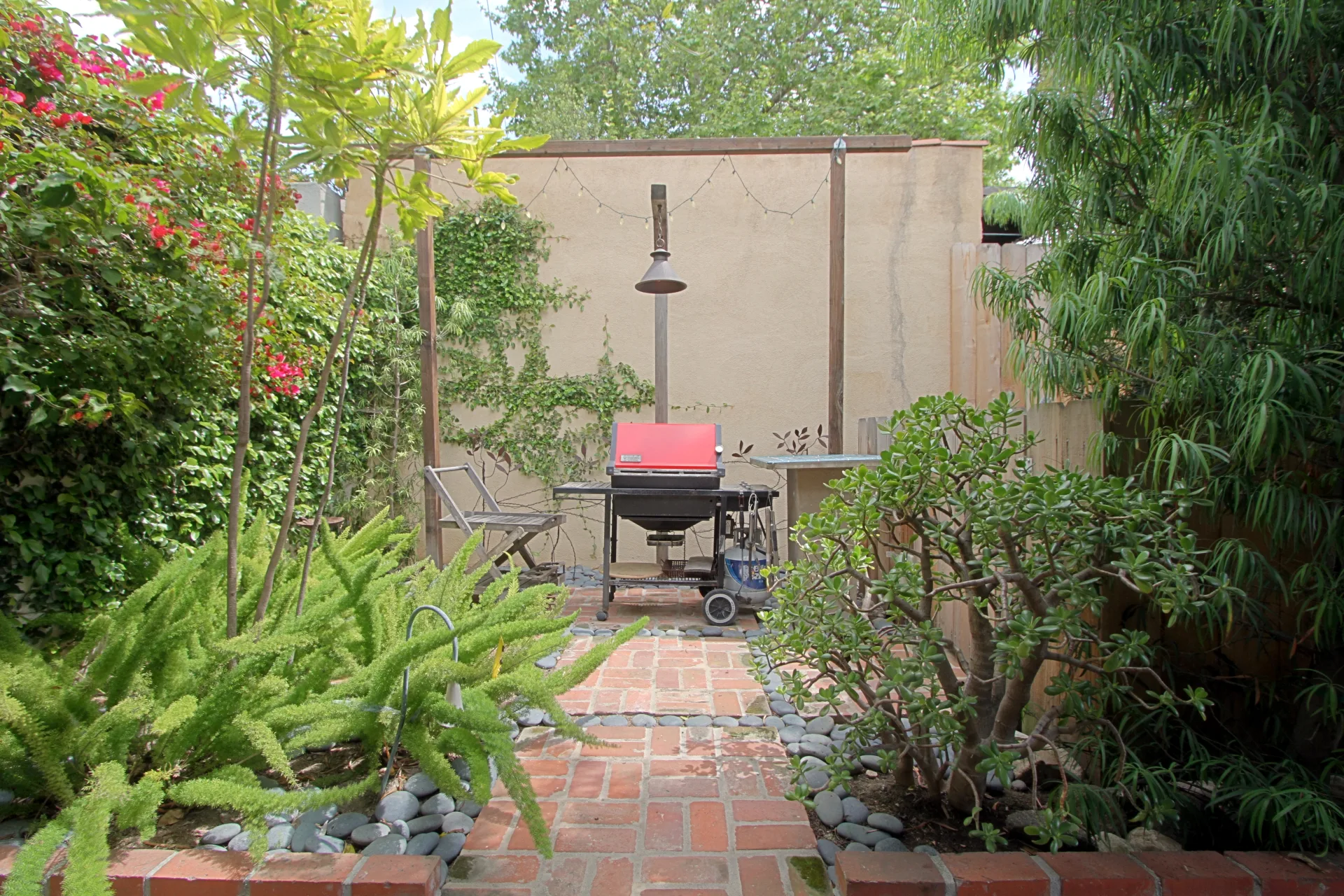 Outdoor entertainment patio with BBQ grill, seating area, and landscaping