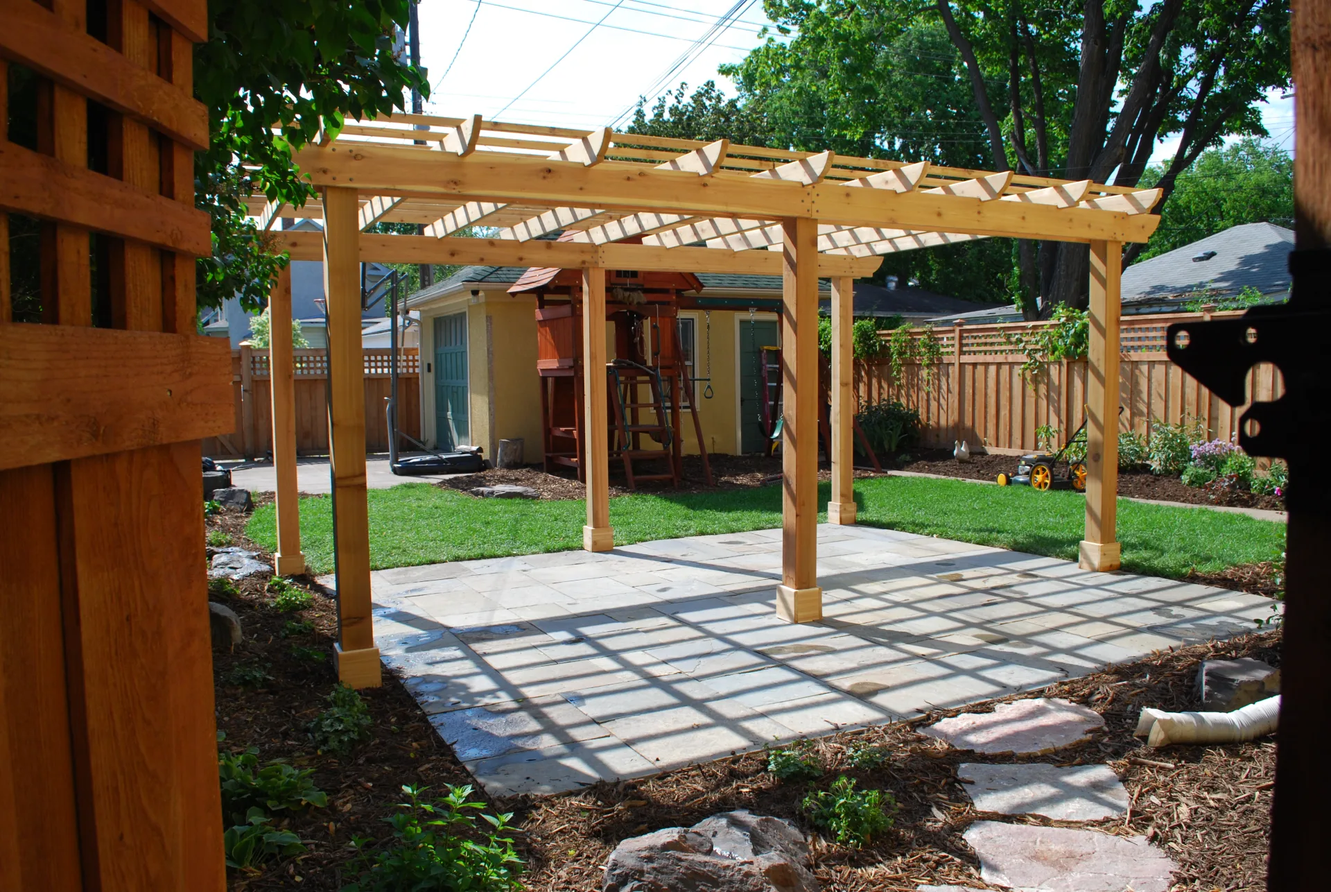Cedar pergola over bluestone patio in a landscaped residential backyard